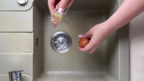 Washing raw eggs with sponge under running water in kitchen sink. cleaning Stock Footage 316472858