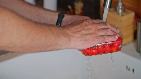 Washing tomatoes over the kitchen sink. Male hands rinse tomatoes under run.. Stock Footage 279544799