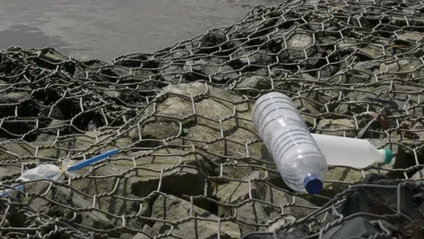 Waste of empty plastic bottles, pollution on local port gabion Stock Footage 137077052