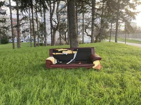 Waste Management - Damaged sofa thrown in the park carelessly. Stock Photos
