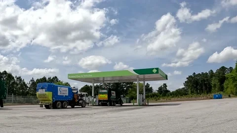 Waste management trash trucks moving in line at a Natural Gas and pumps retai Stock Footage 180135384