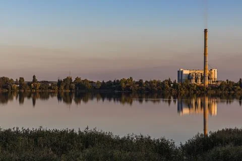 Waste processing plants' chimneys emit smoke at sunset on the lake. Despite Foto stock