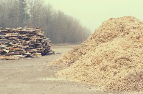 Waste sawmill in the form of a stack of boards and a mountain of sawdust. Stock Photos