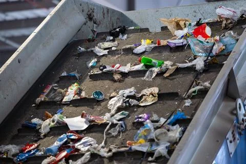 Waste sorting conveyor with mixed plastic and packaging in recycling facility 库存照片