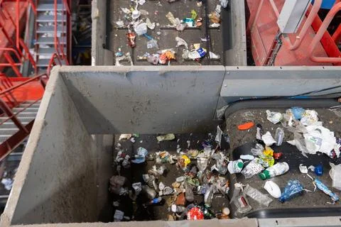 Waste sorting facility conveyor junction with mixed garbage on recycling plan 库存照片