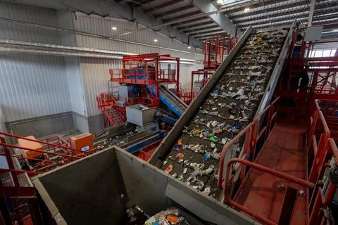 Waste sorting facility interior with conveyor belts and mixed garbage in Stock Photos