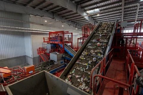 Waste sorting facility interior with conveyor belts and mixed garbage in Stock Photos
