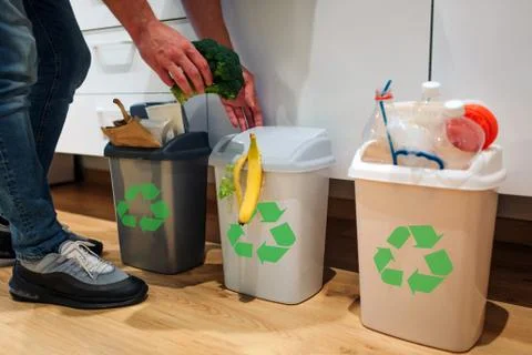 Waste sorting at home. Cropped view of man putting broccoli in the garbage bin Foto stock