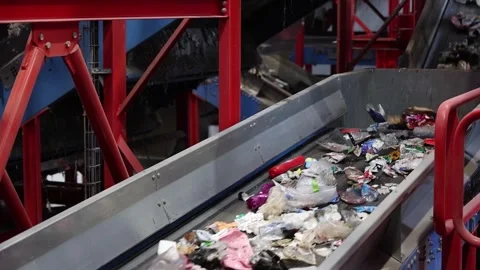 Waste stream advancing through conveyor section inside recycling structure Stock Footage 333345254