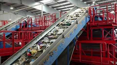 Waste stream carried through upper conveyor pathway in recycling facility Stock Footage 333345219
