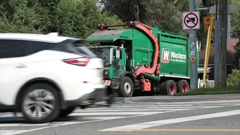 Wasteco making a meterial difference green orange garbage truck parked on side Stock Footage 251355905