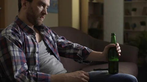 Wasted guy sitting on couch, drinking beer, alcoholism, psychological problems Stock Footage 84879949