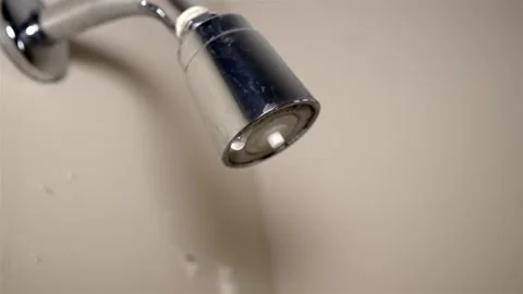 Wasted water drop falling from a shiny chrome bath fixture Stock Footage 323815861