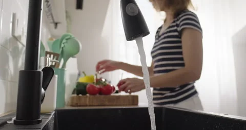 Wastewater, water flows from the tap while woman prepares vegetables in the Stock Footage 267033871