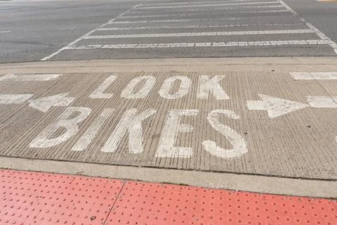 Watch Bikes warning painted on pavement at a pedestrian crossing Stock Photos