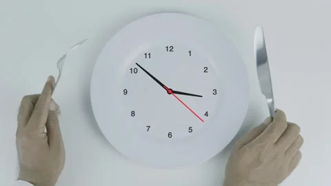 Watch Clock Time Concept on plate and hand holding fork and knife on white Stock Footage 313968700