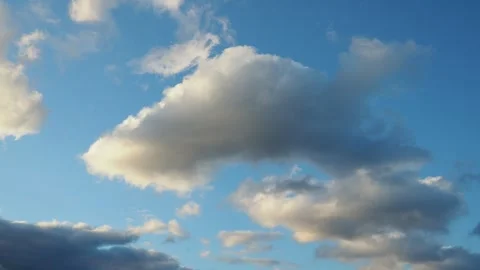 Watch as clouds change shape and drift across the bright blue sky during the day Stock Footage 343734277