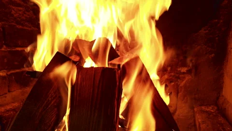 Watch flames dance in the fire as logs burn brightly in a home fireplace during Stock Footage 344319912