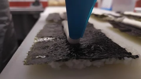 Watch as the master chef skillfully adds Philadelphia cheese to sushi rolls Stock Footage 268741529