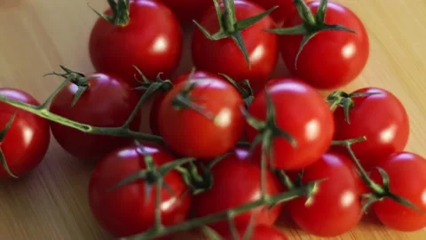 Watch the mesmerizing dance of cherry tomatoes on a wooden cutting board Stock Footage 231334538
