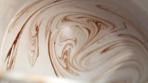 Watch as thick cream blends smoothly with coffee syrup, creating a beautiful Stock Footage 292756573