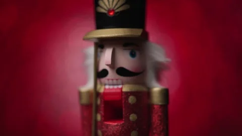 Watch the Toy Nutcracker twirl lively and defocused in front of a vivid red Stock Footage 321681017
