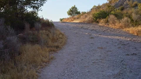 Watch a trail winding through a hillside during the late afternoon in a dry.. Stock Footage 340190555