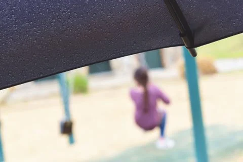 Watching children play while under a raindrop soaked umbrella Foto stock