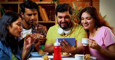 Watching comedy video in cafe, Indian college students laughing while snacking Stock-Footage 342384252