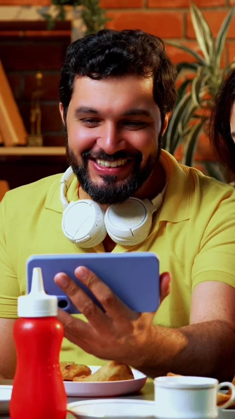 Watching comedy video in cafe, Indian college students laughing while snacking Stock Footage 342385129