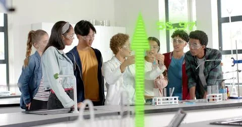 Watching instructor wearing white coat holding glass vial at school lab bench, Stock Photos