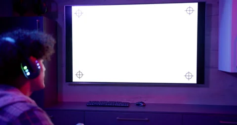 Watching large screen, man with headphones sitting at desk with keyboard and Stock Footage 300071245