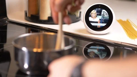 Watching The News While Cooking On a Smart Assistant Device Amazon Echo Spot Stock Footage 94032282