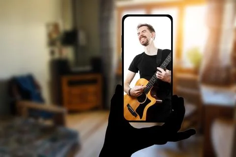 Watching online music performance by the singer at home by smartphone. Stock Photos