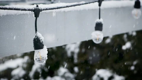 Watching the snow fall on string lights in the backyard during a winter Stock Footage 148249576