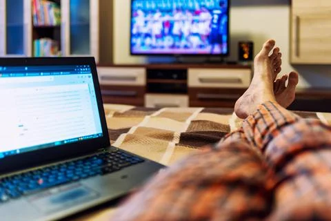 Watching TV and notebook screen at home Stock Photos