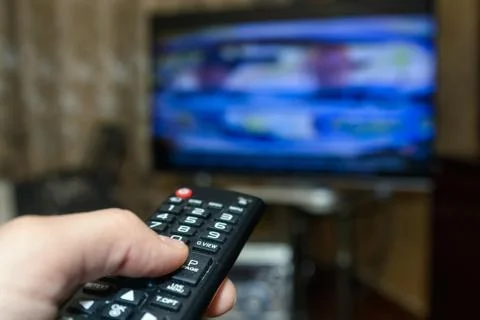 Watching TV and using remote controller Stock Photos