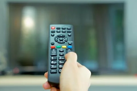Watching TV and using remote controller Stock Photos