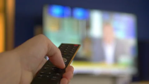 Watching tv and using TV remote control in 4k Stock Footage 143681020