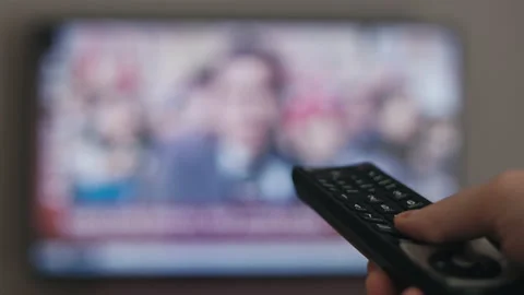 Watching TV, hand with the remote control in front of the TV, watching news Stock Footage 239274196