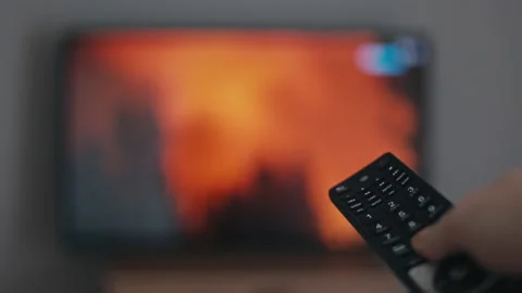 Watching TV, remote control in hand, news about forest fires and disasters Stock Footage 239273858