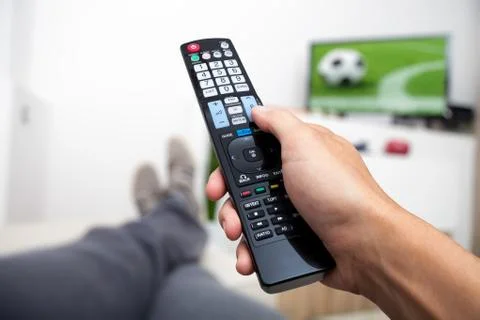 Watching TV. Remote control in hand. Watching football on TV. Man lying on th Stock Photos
