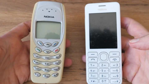 Watching two old Nokia  mobile phones. Nokia 3410 and 206 outdated mobile phones Stock Footage 191141344