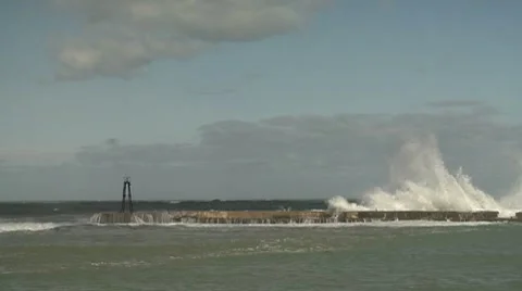 Watching wave wash down seawall towards small lighthouse Stock Footage 8509736