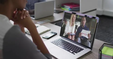 Watching worker viewing silver laptop in office, hosts showing chart, woman in Stock Photos