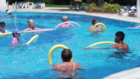 Water Aerobics Class in a Sunny Pool With Participants of All Ages Enjoying Stock Footage 312272092