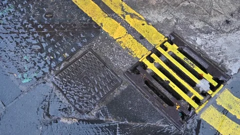 Water after a downpour flowing down from the manholes of a street in the city Stock Footage 228301059