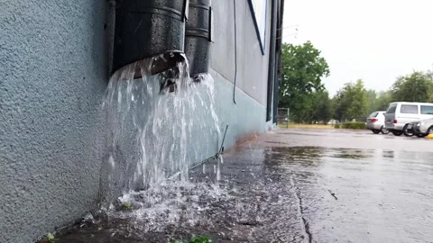 Water after rain pours from a drainpipe on a building against the backdrop of Video stock 297849770