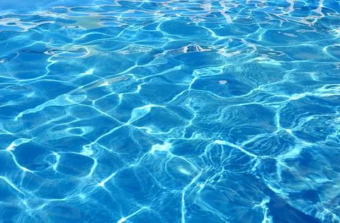 Water background of the pool with the effect of small ripples and sunlight. Stock Photos
