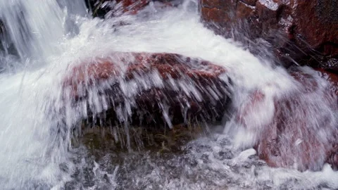 Water beats with force against a large round stone Stock Footage 231286628